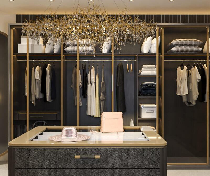 Opulent walk-in closet interior design featuring black textured drawers and golden racks filled with luxurious garments and accessories, illuminated by a grand chandelier